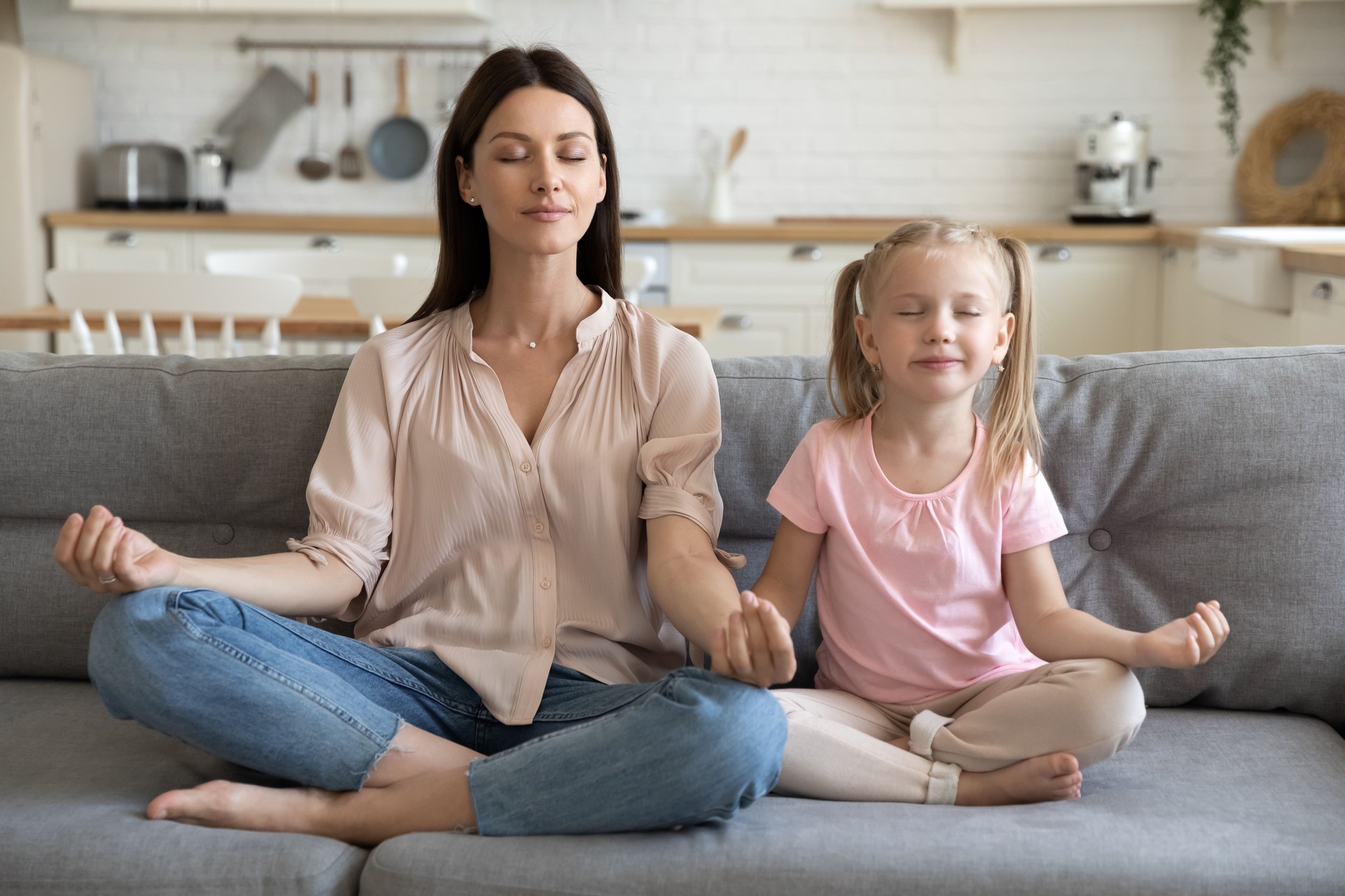 Fille saine de maman et d'enfant faisant l'exercice de yoga sur le sofa